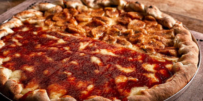 A freshly baked pizza with melted cheese, topped with toppings, served on a tray with a golden crust.