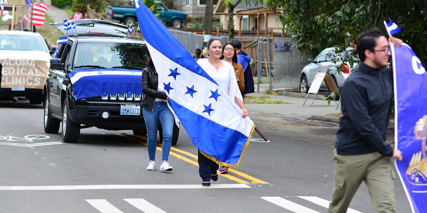 Hondurans celebrating Día de la Independencia with flags, parades, and traditional dances on vibrant city streets