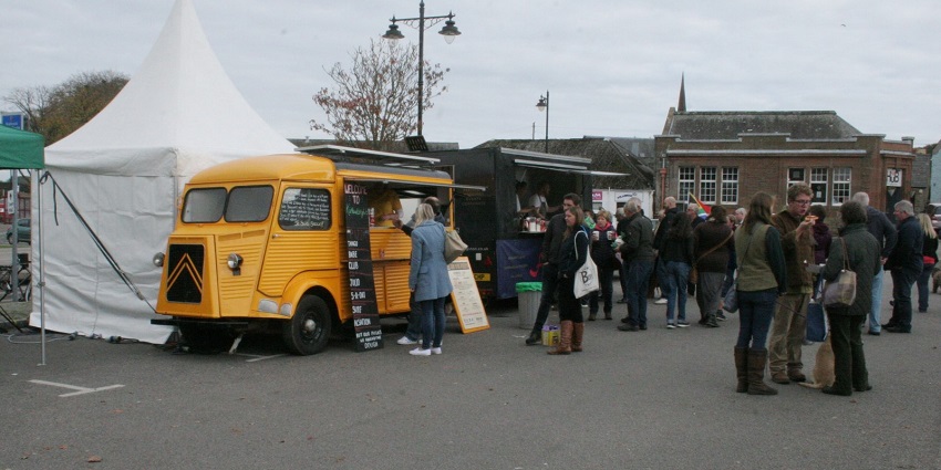 People stand near a food truck set up during a food festival in the United Kingdom.