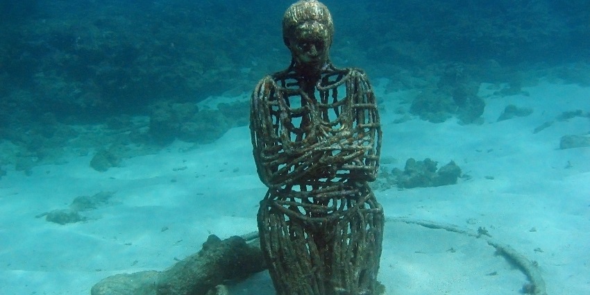 Stunning underwater sculptures of children standing while holding hands in clear blue water