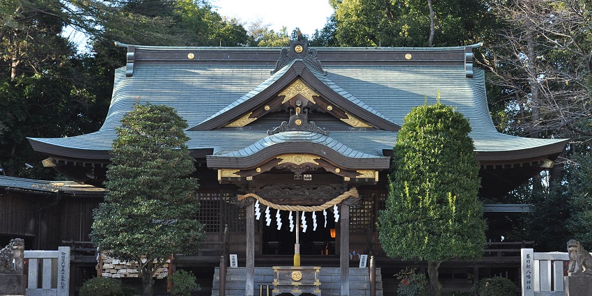 Wooden shrine building with a clean gravel path and red banners, cultural things to do in Kasukabe.