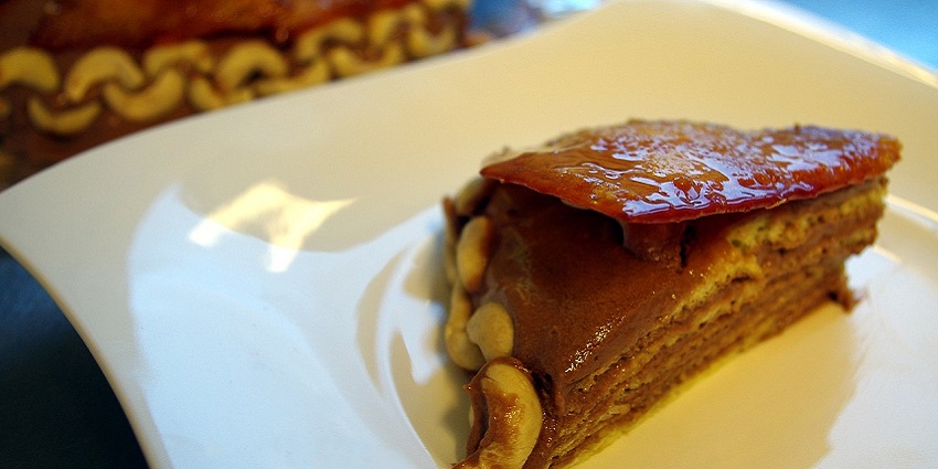 An image showing Dobos Torte sliced to show sponge layers and a hard caramel top.