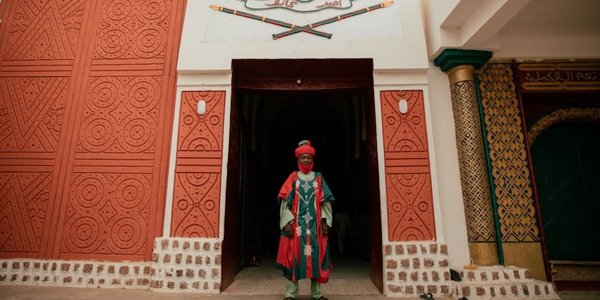 Man wearing traditional attire at mosque entrance during Durbar Festival.