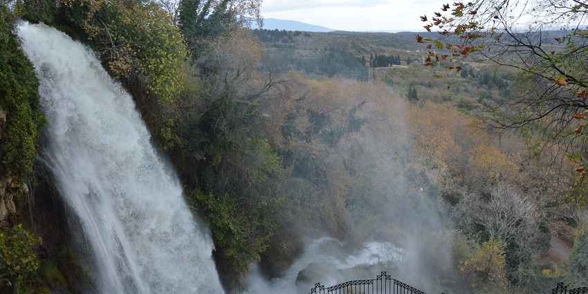 Edessa Waterfalls in northern Greece cascade over a cliff, surrounded by trees and stones.
