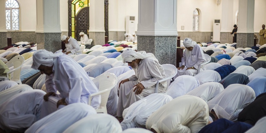 Omani men performing Eid al-Adha prayer together inside a mosque, showing devotion.