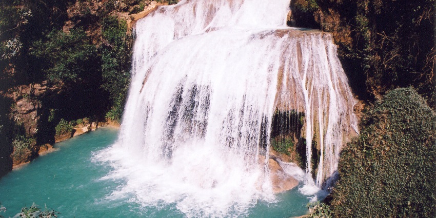 El Chiflón waterfall, surrounded by verdant cliffs, cascades into a turquoise lake.