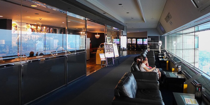 Modern indoor observation lounge with leather seating, large windows, and a café offering 360 degree views.