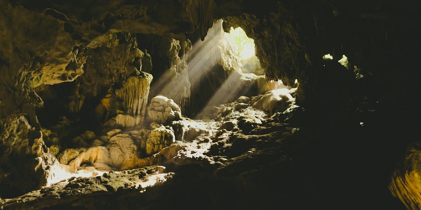Sunlight pierces through a cave in Quảng Bình, Vietnam, illuminating ancient formations.