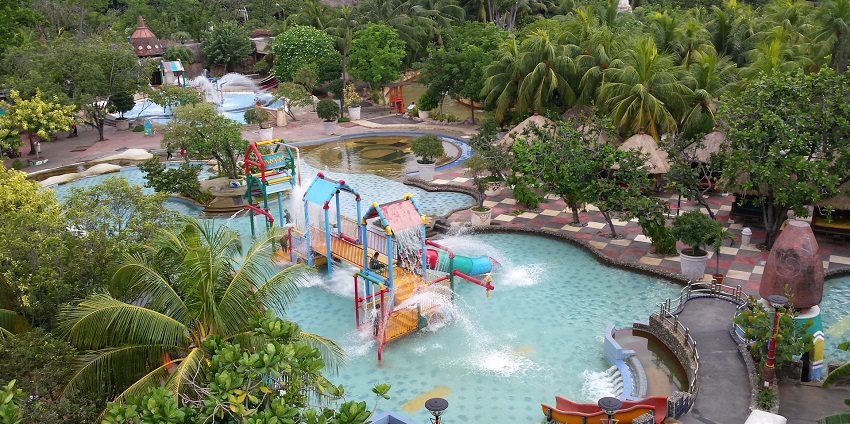 People enjoying thrilling amusement park rides with vibrant lights at a water park in Mohali
