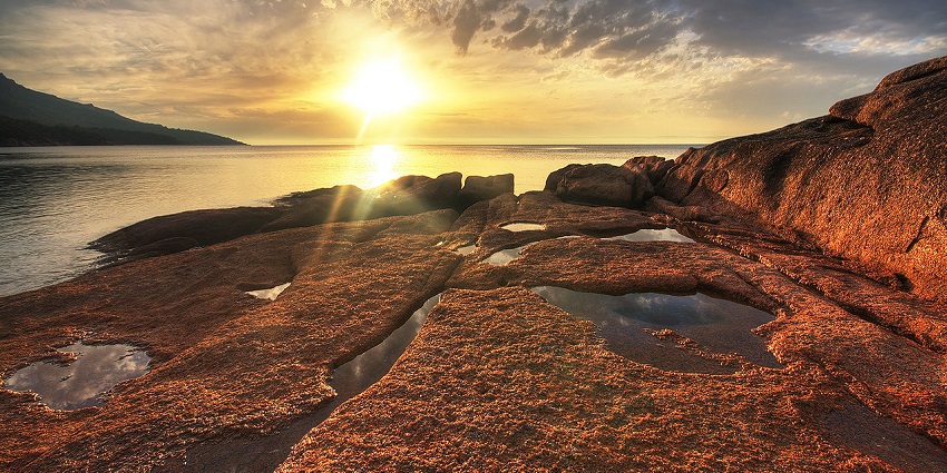 The stunning sunset view looks unrealistic by the beach with an orange sky and grey clouds