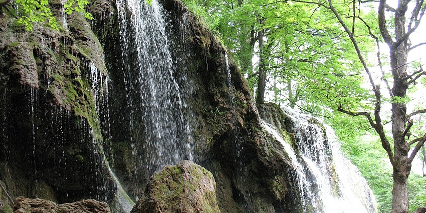 Etropole Waterfall (Varovitets) cascading over mossy rocks in a serene forest setting