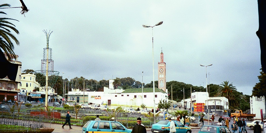A glimpse of the iconic Grand Socco teeming with people, cars, and quaint buildings.