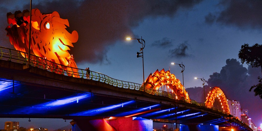 Reflection of the Dragon Bridge in calm river water at twilight, creating a mirror-like effect