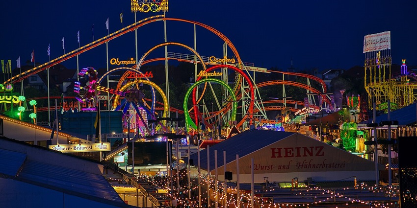 Oktober festival at night with vibrant roller coaster tracks, multiple flags, signages and banners