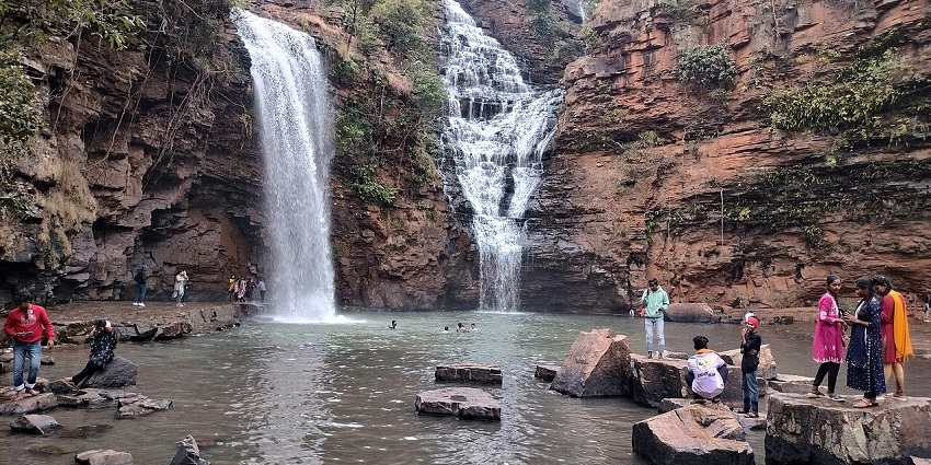 Waterfall surrounded by many visitors enjoying the view and taking photos near the pool