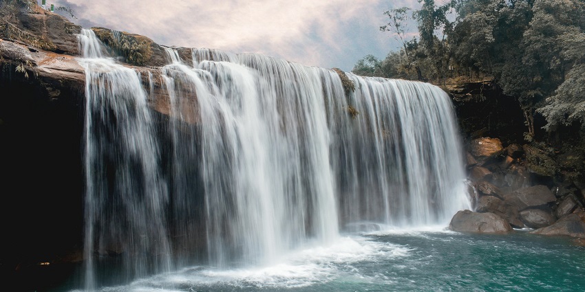 A stream of water cascades down a rugged cliffside, surrounded by moss-covered rocks.