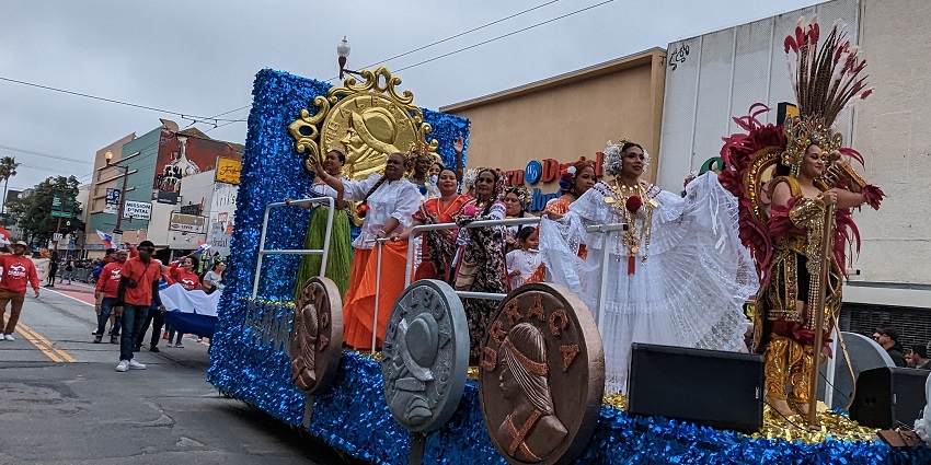 A group of women dressed in vibrant attire rides a chariot-like vehicle during a fair