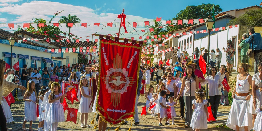 Young girls and women dressed in white carrying a big red flag and parading in the festival