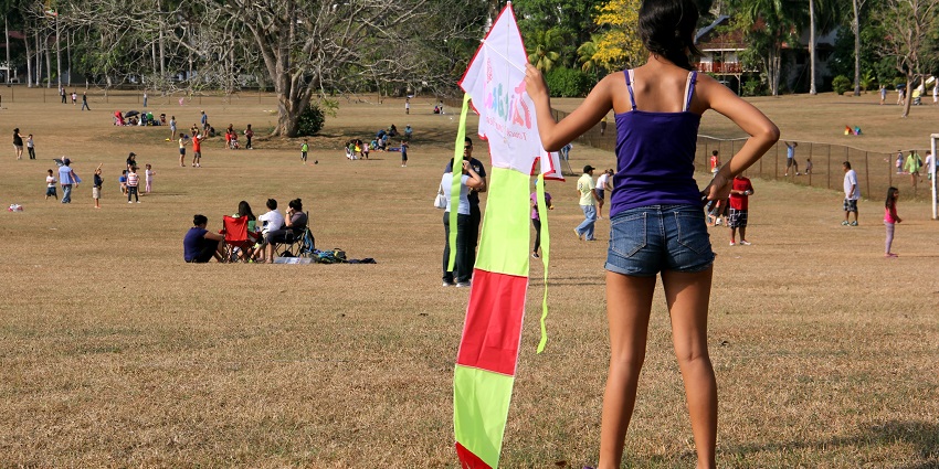 A girl holds a kite with a long tail during a relaxing day at a carnival in Panama