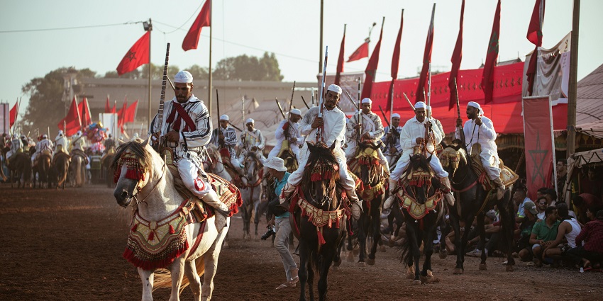Men clad in white beat the drums with sticks and hands, displaying their musical talents