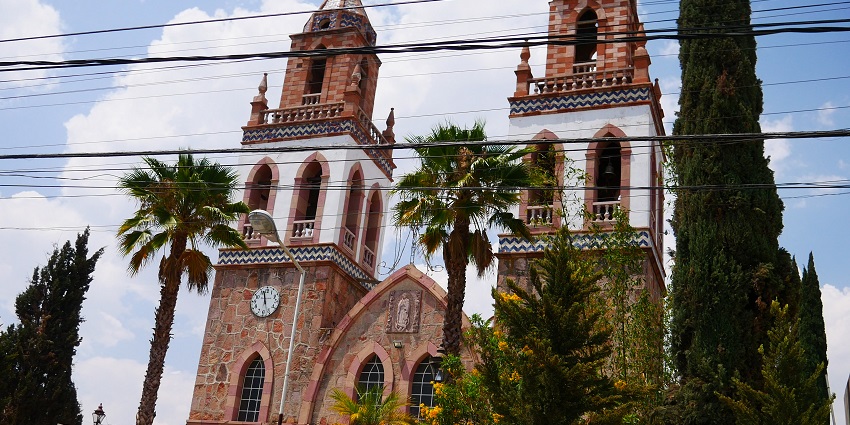The twin-towered stone church stands tall, framed by palms and bright blue skies.
