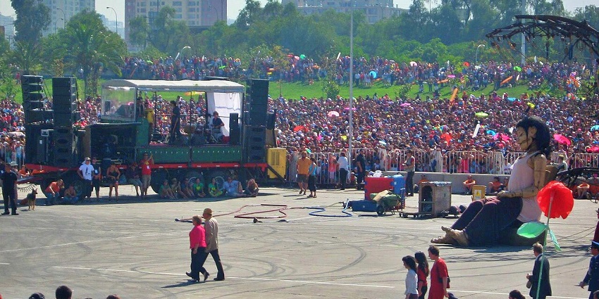 Chileans wave flags during Fiestas Patrias, surrounded by cueca dancing and food stands.