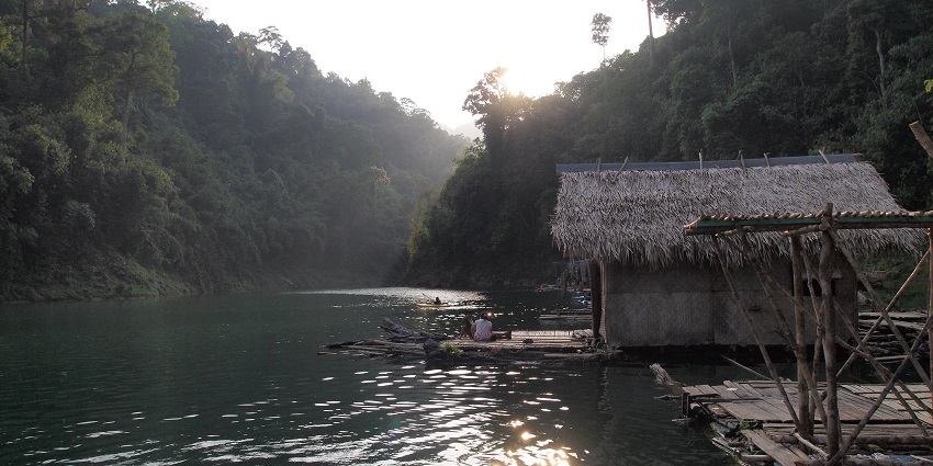 Tranquil reservoir surrounded by cliffs and forests, known for floating bungalow stays.