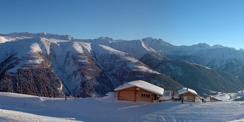 Goms Valley covered in snow with mountain peaks and traditional alpine houses in the landscape.