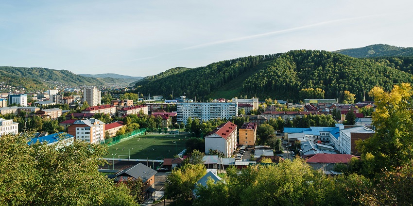 A bird's-eye view of the scenic town of Gorno-Altaysk with fluffy clouds hovering over it.
