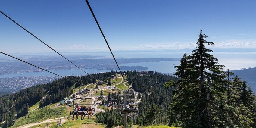 A panoramic view of Grouse Mountain with people enjoying the beauty on a cable car.