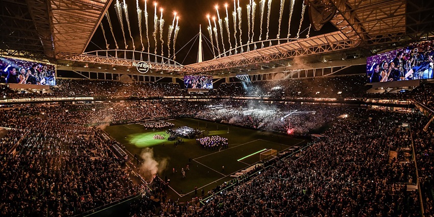 Hard rock stadium with lit fireworks in the sky, multiple big screens and a fully packed crowd