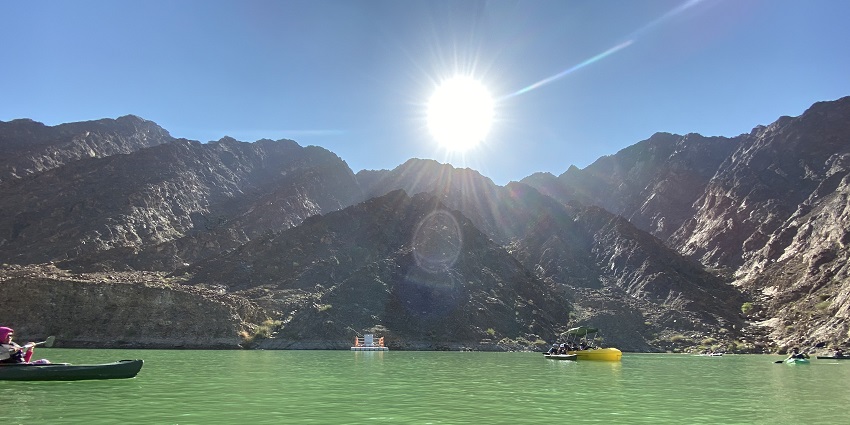 The sun shining bright above the Hatta dam is captured by a person kayaking on the green waterways.