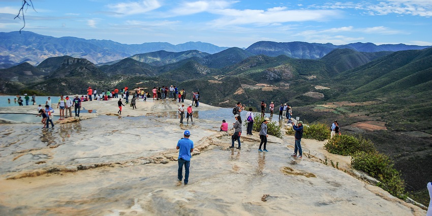 Hierve el Agua with a lot of visitors clicking pictures and enjoying the mountain view