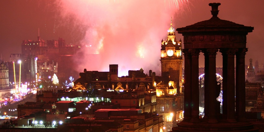 A display of brilliant fireworks makes the sky red over the landscape of Edinburgh