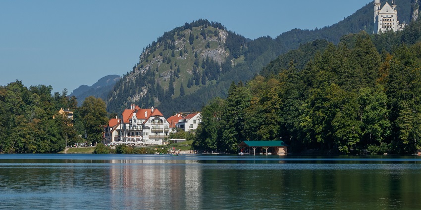 A view of the Hohenschwangau Castle behind beautiful waters, displaying its grandeur.