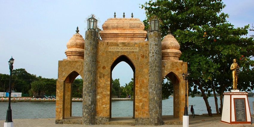 View of a intricately carved gate, with lush trees and clear blue sky in the background