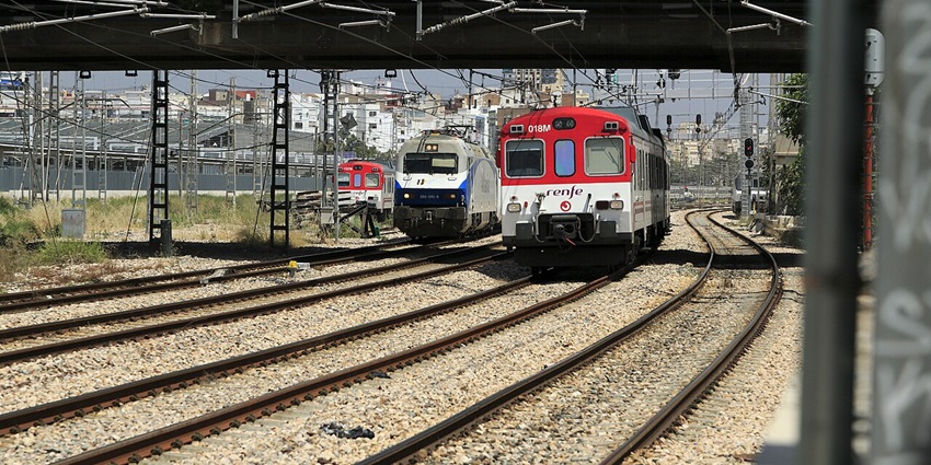 Trains on the railway track reaching the station and a bridge above with a car passing