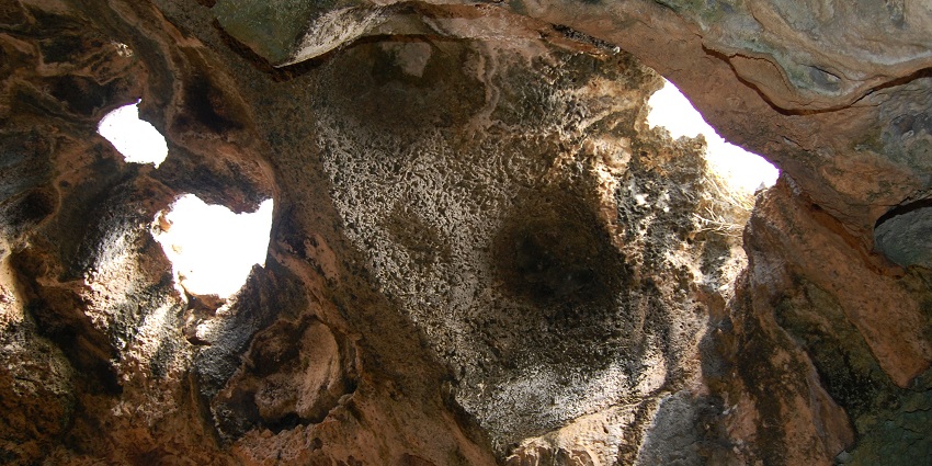 An image of a very narrow passage with bright light spots, inside one of the Aruba caves.