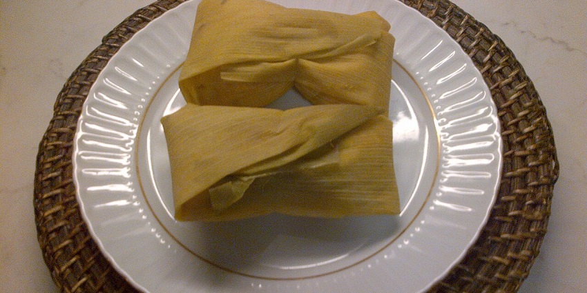 An image showing a view of Humitas, corn dough wrapped in corn husks and steamed.