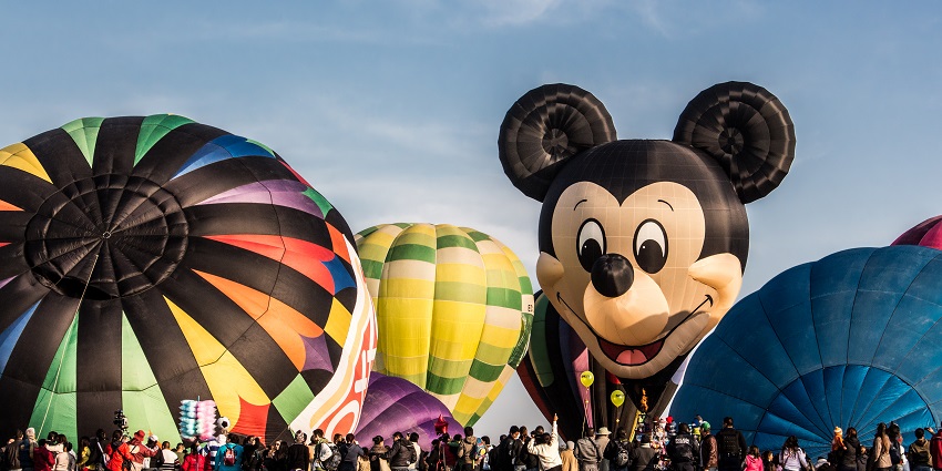 Crowds gather at hot air balloon festivals with vibrant balloons and Mickey Mouse design