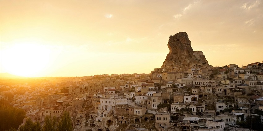 An old castle glows as the sun sets in the distance, creating an orange-yellow glow