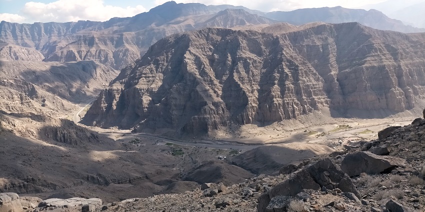 A panoramic view of snow-clad mountain ranges with a half-dry river flowing relentlessly.