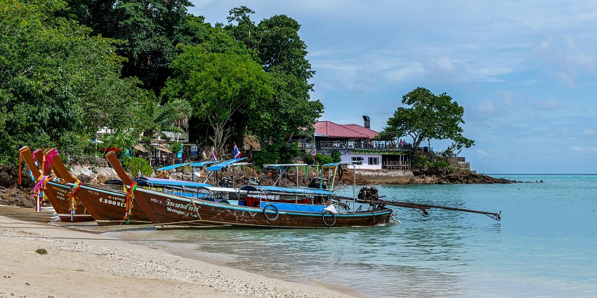 A stretch of golden sand and blue water at Karon Beach in Phuket under a sky.