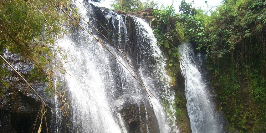 Katieng Waterfall in Cambodia flowing through lush green landscapes and rocky terrain.