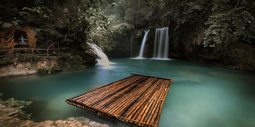 A raft floating in the turquoise water of Kawasan Falls, Cebu, surrounded by lush greenery