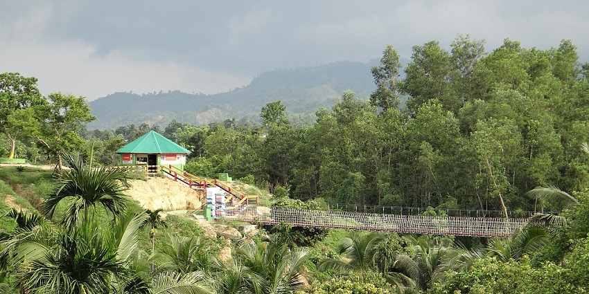The mesmerising view of a hanging bridge and a hilltop house surrounded by lush greenery.