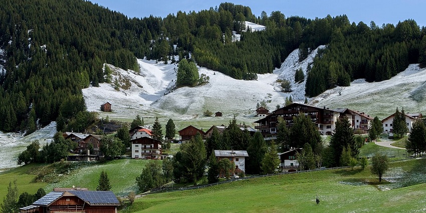A beautiful scenery of nature in its best version, with small houses beneath a clear blue sky.