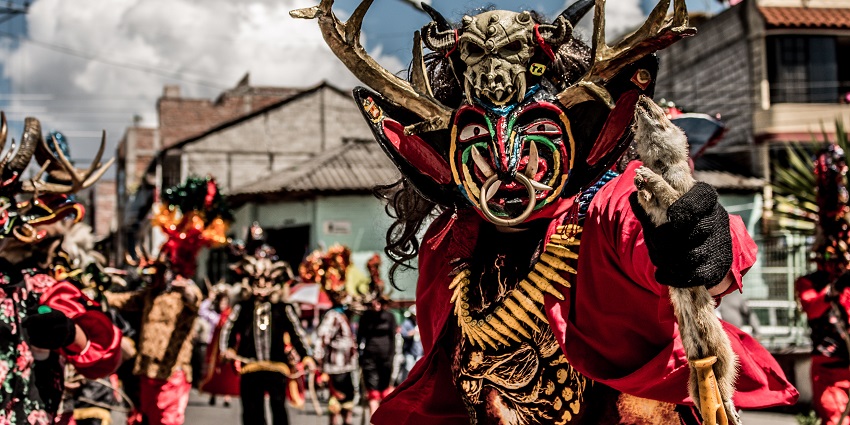 Peruvian dancer in vibrant Diablada costume performs during a traditional street festival in Peru.