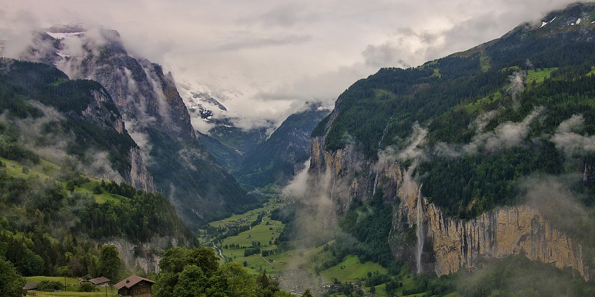 Lauterbrunnen Valley with misty mountains, green hills, and town in valleys in Switzerland.