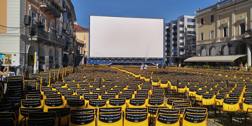 Rows of bright yellow chairs set up in a town square for an outdoor film festival.